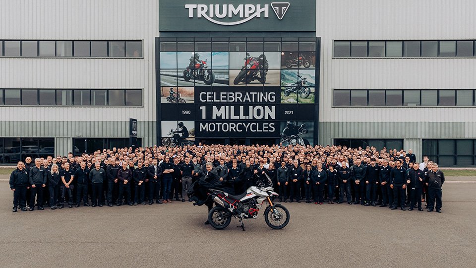 Triumph employees standing in front of building headquarters with a motorbike