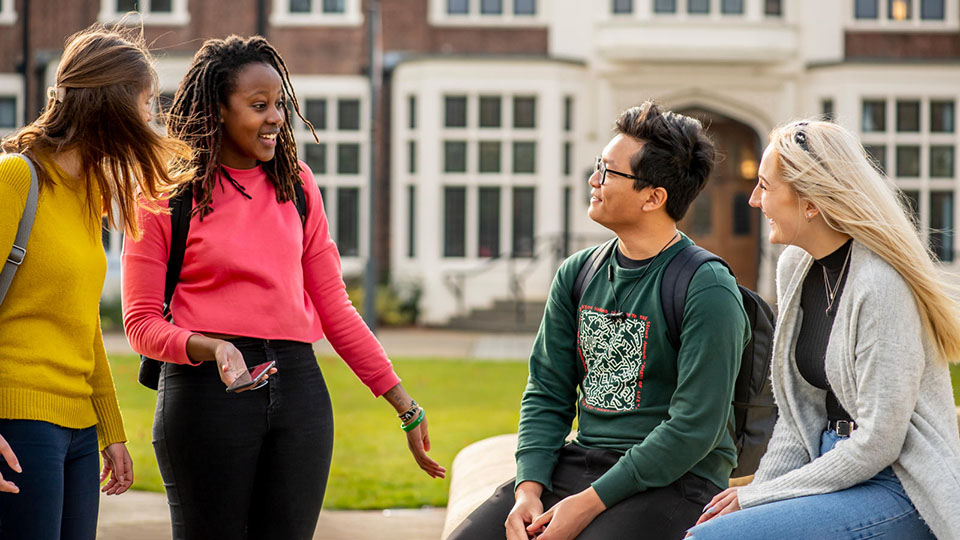 Four students talking by the fountain at Loughborough University