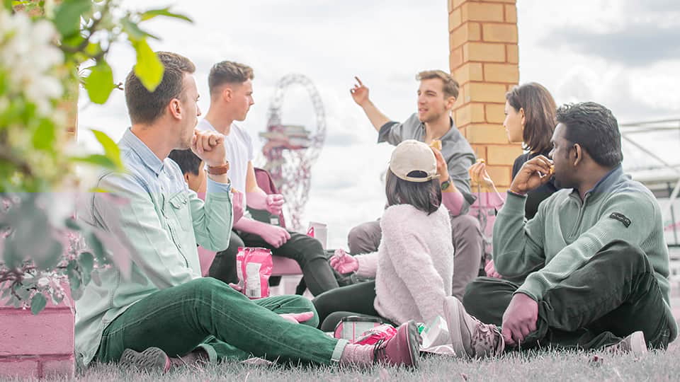 a group of people sitting on the grass talking