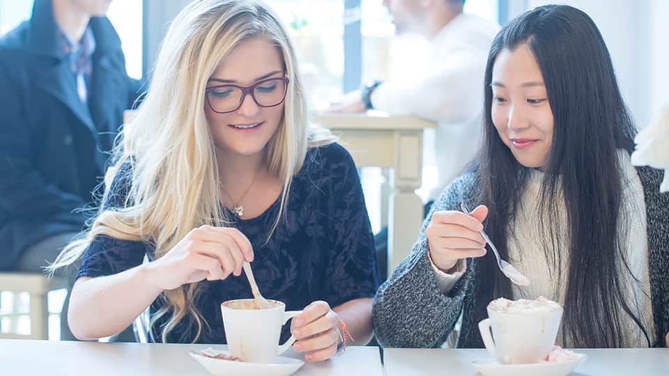two women sitting in a cafe drinking coffee