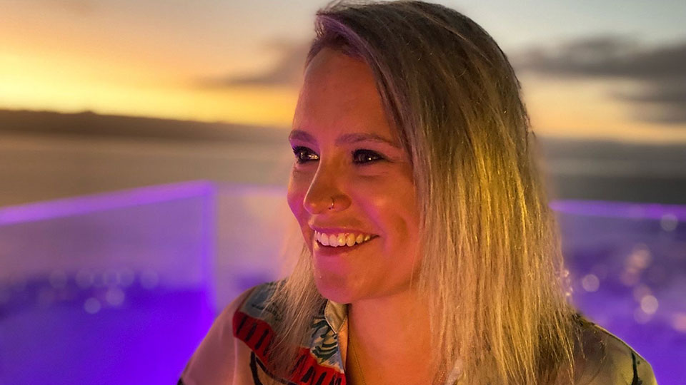 A photo of angelique smiling in front of a sunset