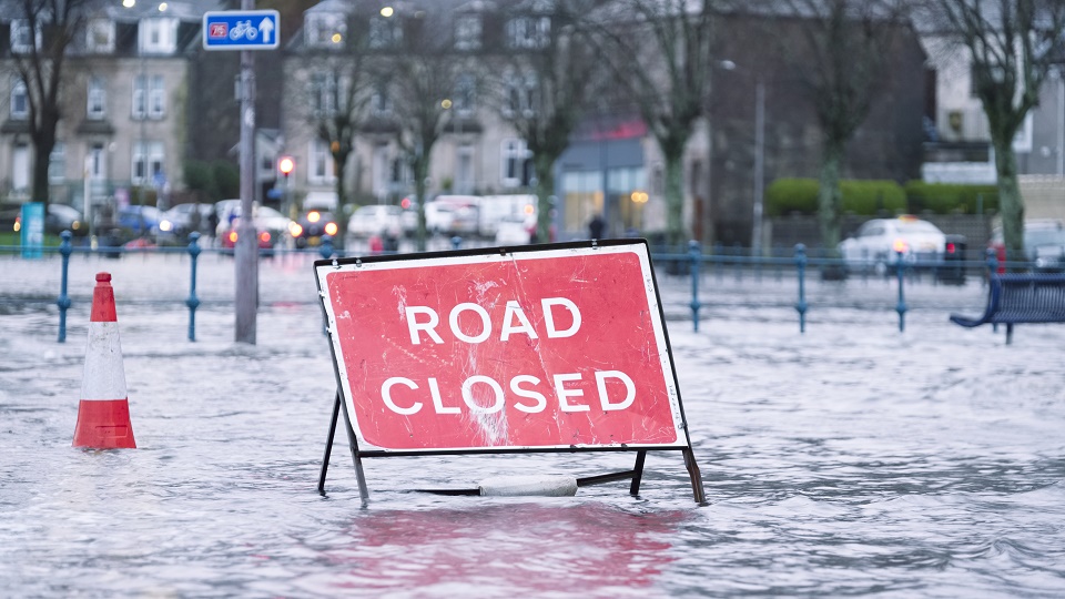 A 'Road Closed' sign is sat in floodwaters.