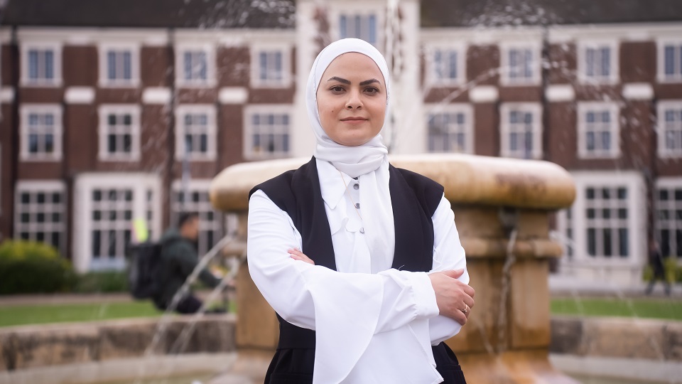 International student Dua'a is stood in front of the University fountain.