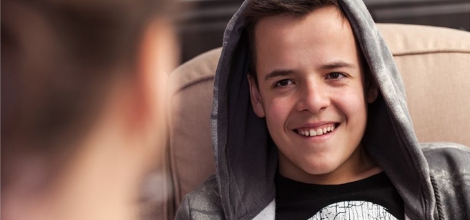 A boy smiling, talking to an adult