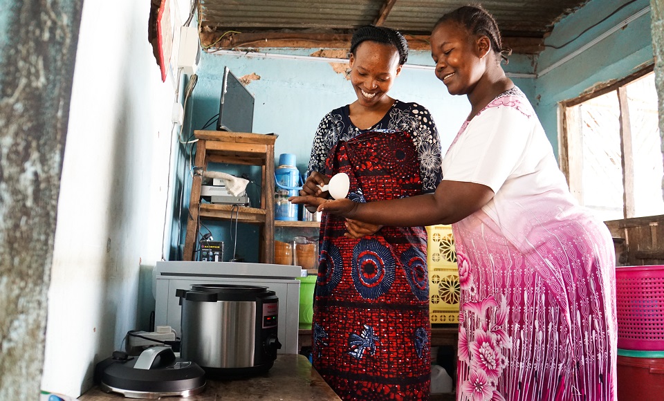 Two women cooking in a kitchen using an electric cooker