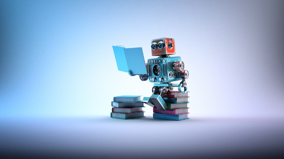 A robot sat on top of a pile of books reading a blue book