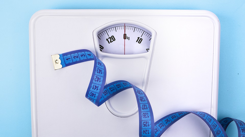 A set of scales with a blue tape measure draped across it.