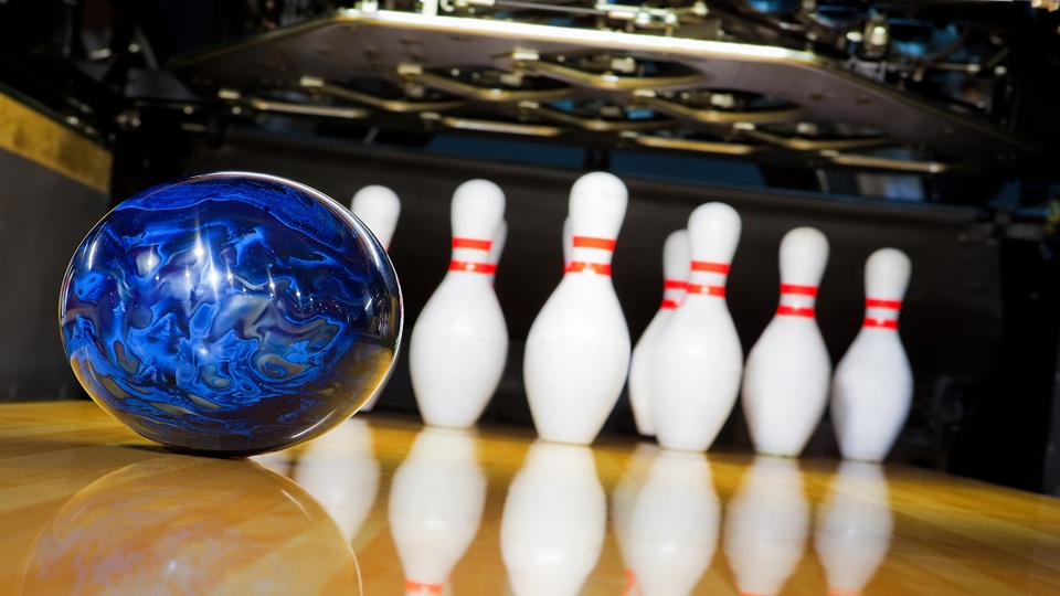 A blue bowling ball next to some pins.
