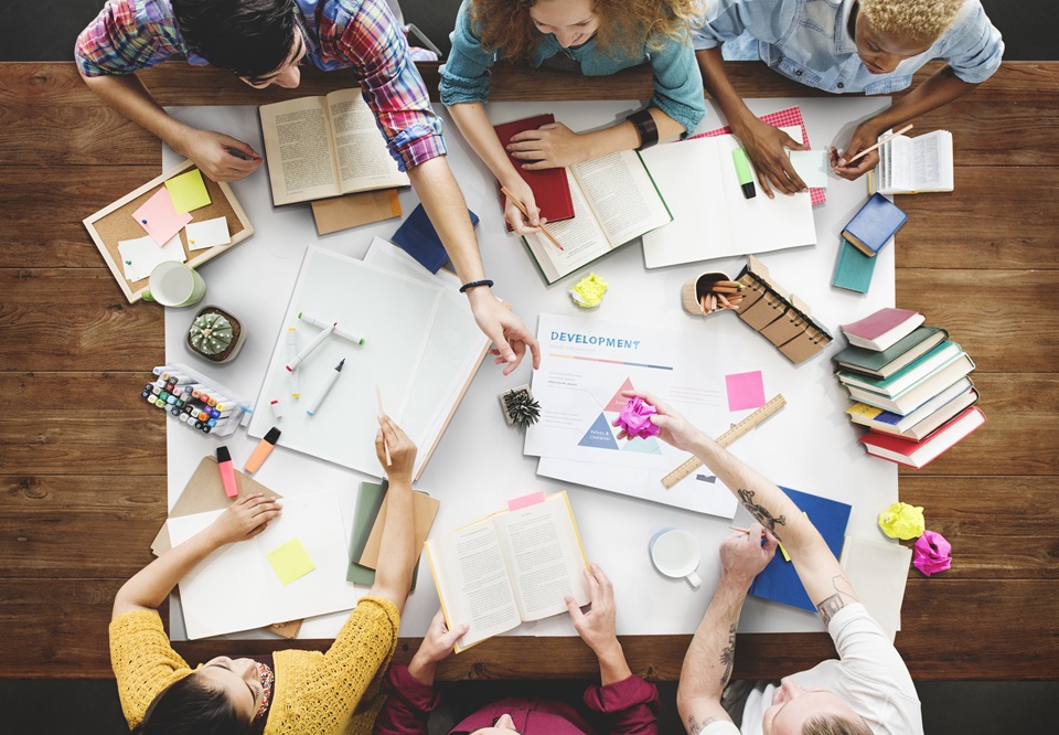 A group of people are sat around a table discussing work and projects