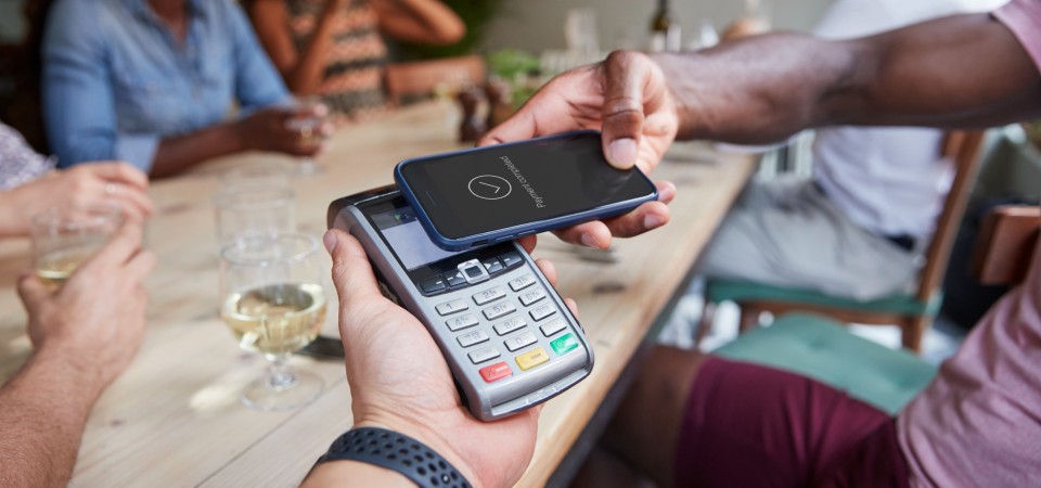 A man pays for dinner with a banking app on his phone