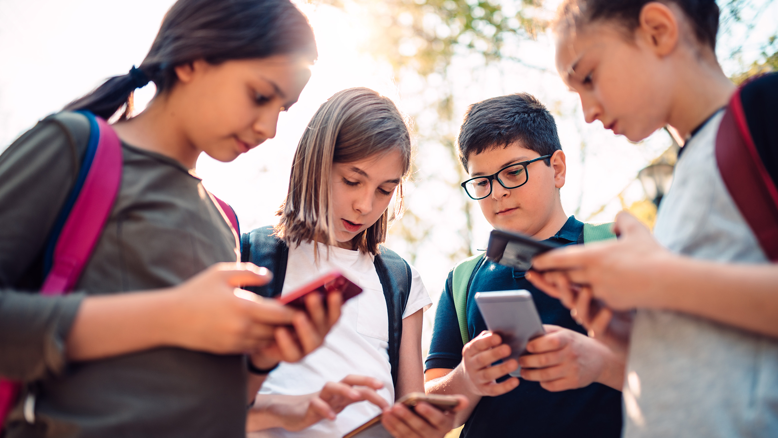 A group of four children looking at mobile phone devices