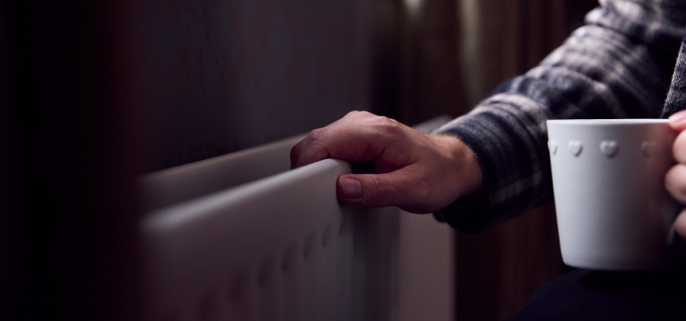An old hand on a radiator in a gloomy house