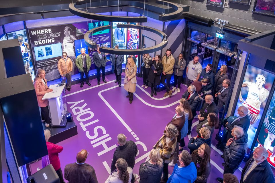 A group of people stand together at the Gateway to Sport entrance to the Sir David Wallace Sports Hall