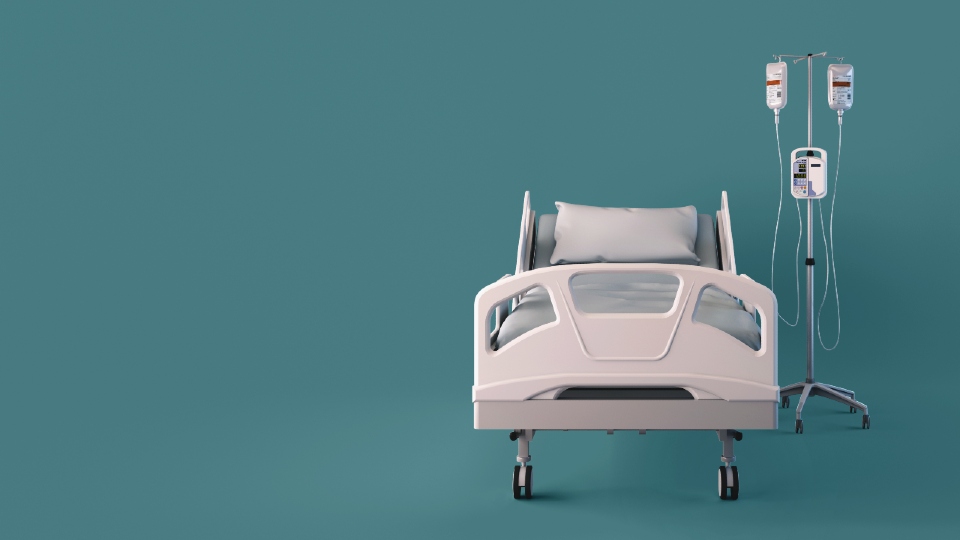 A white hospital bed with a stand with drips on a teal background