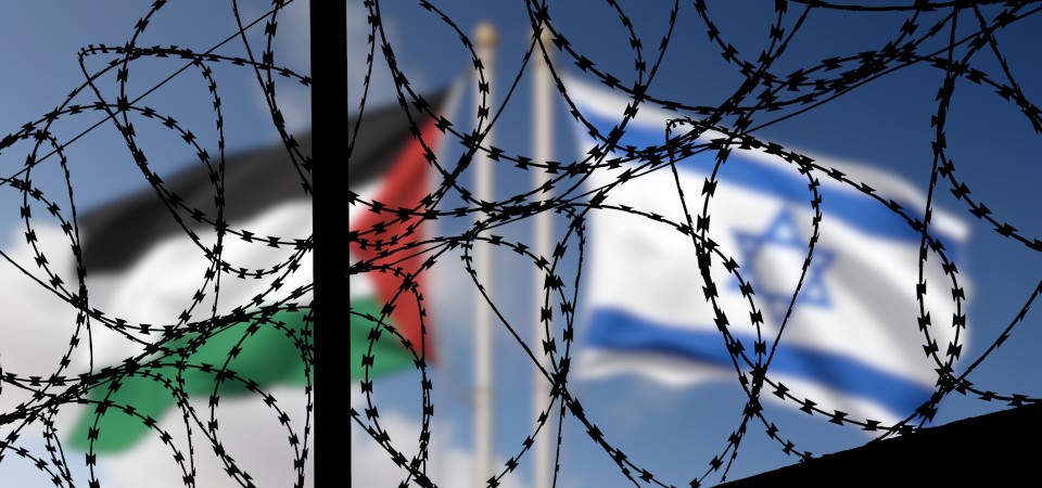 Flags of Israel and Palestine fly behind barbed wire