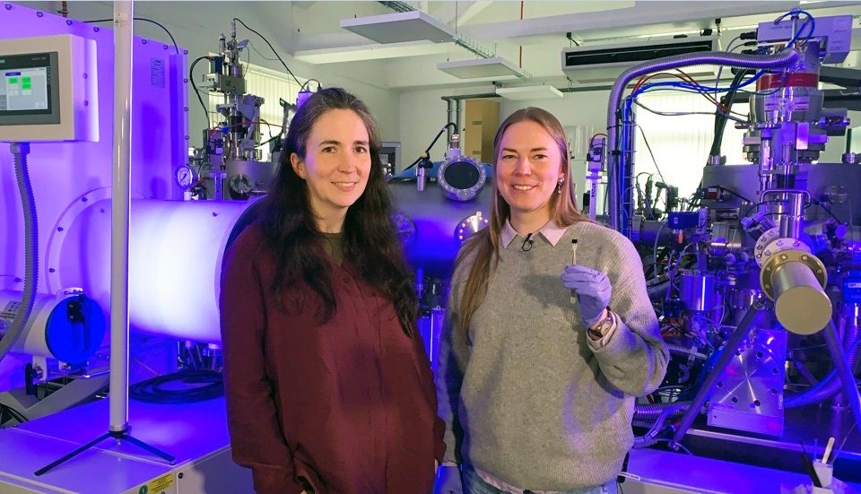 Professor Kelly Morrison, left, with Dr Naëmi Leo, in front of the Loughborough University nanolithography system. Dr Leo holds the chip that features the image of ‘the world’s smallest violin’.