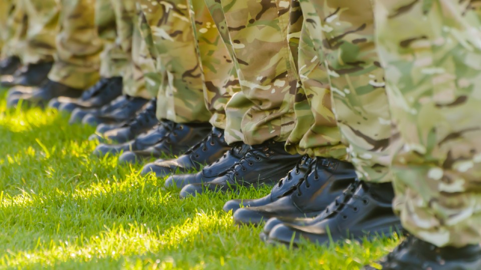 People stood in a line wearing military boots and camo trousers