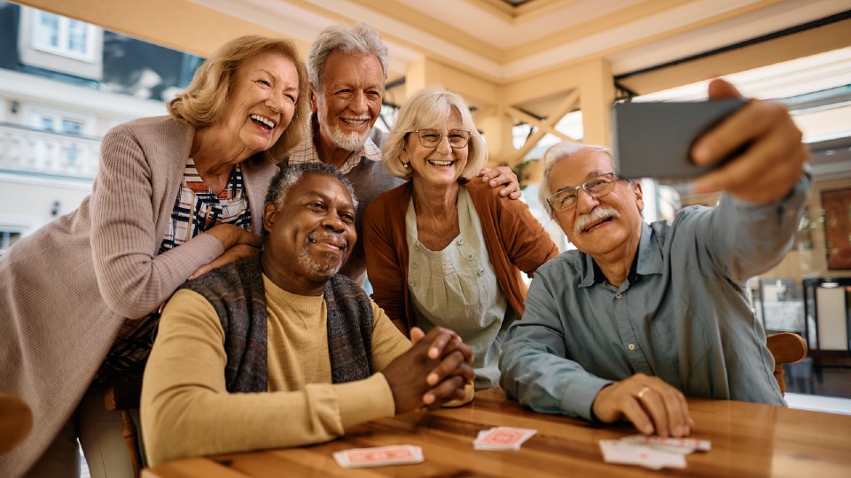 A group of elderly friends taking a selfie with a phone