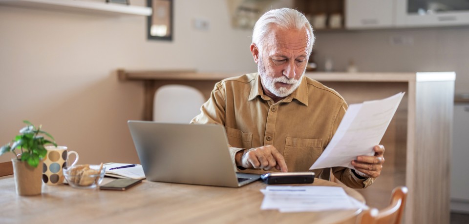 A man with white hair does his finances with a calculator
