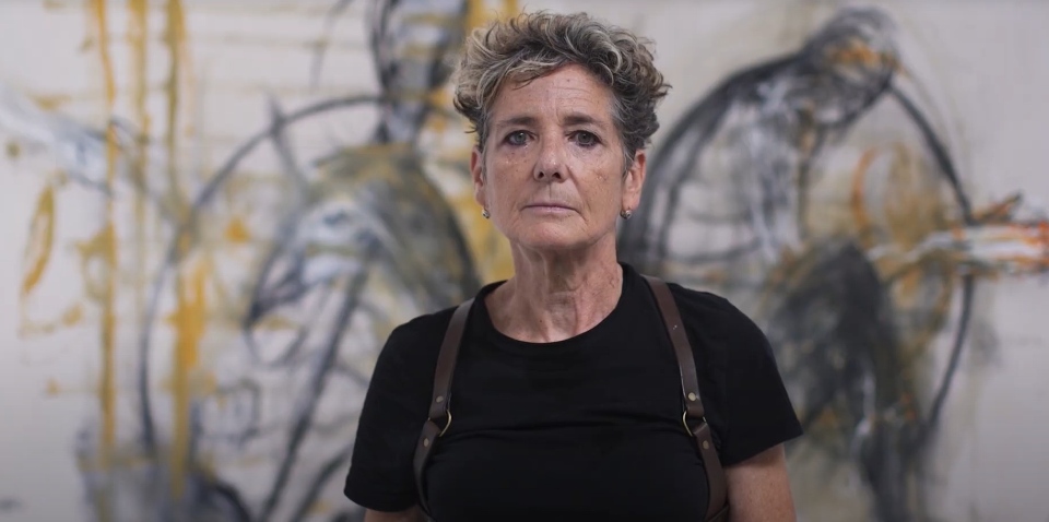 Rachel Gadsden in front of a large white canvas with black markings on it