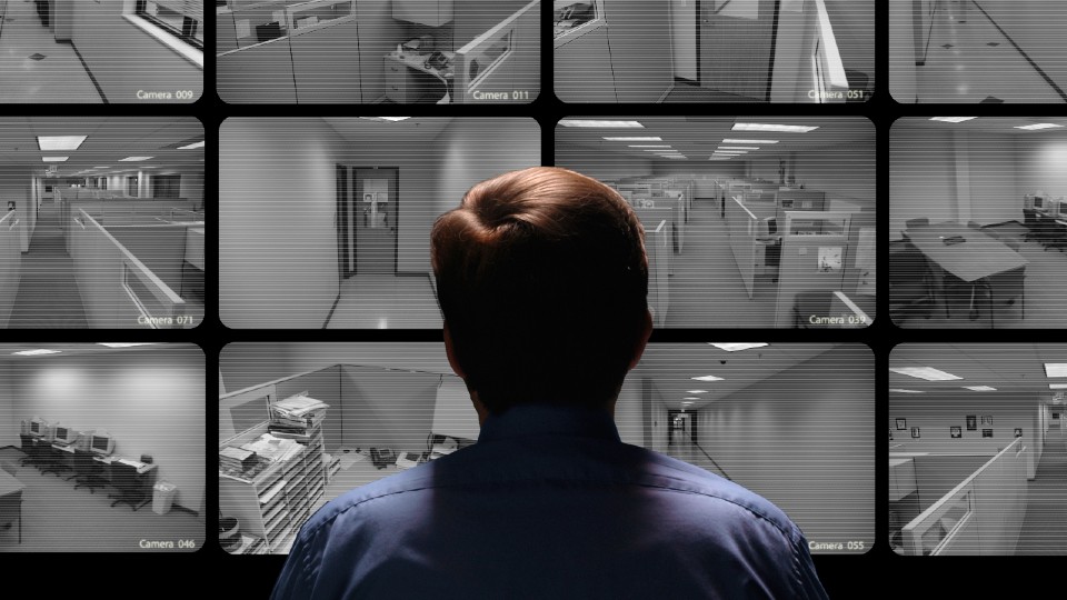 A man facing several security cameras showing different locations in an office