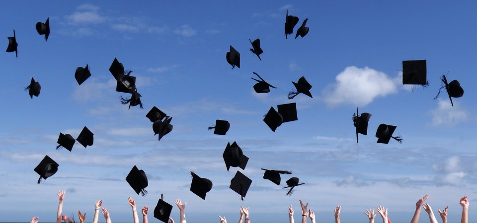 students throw their mortar boards into the air