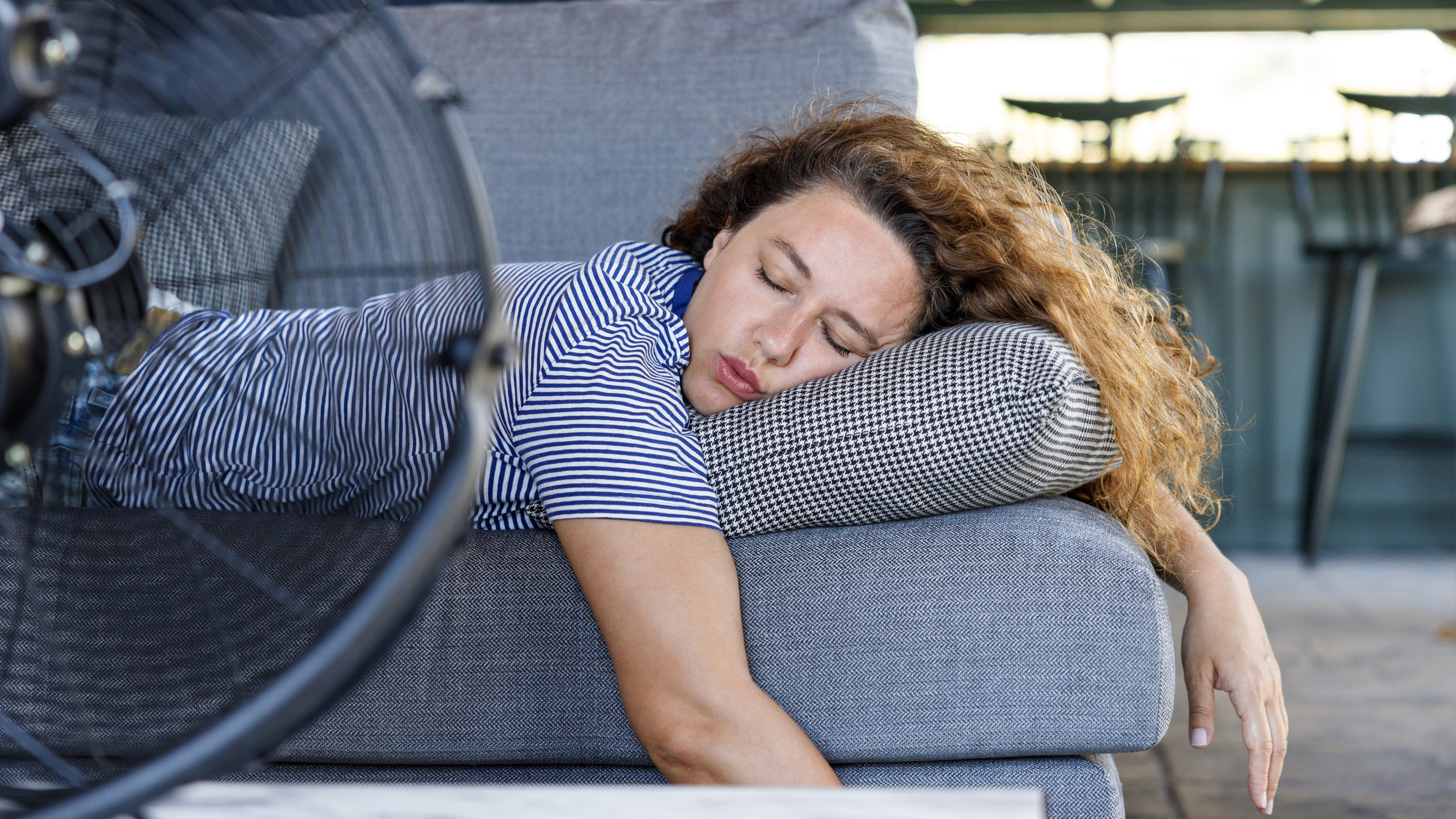 woman laid on sofa in front of fan