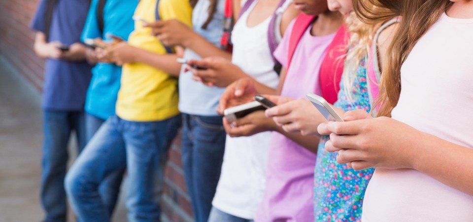 A line of youngsters all looking at the phones