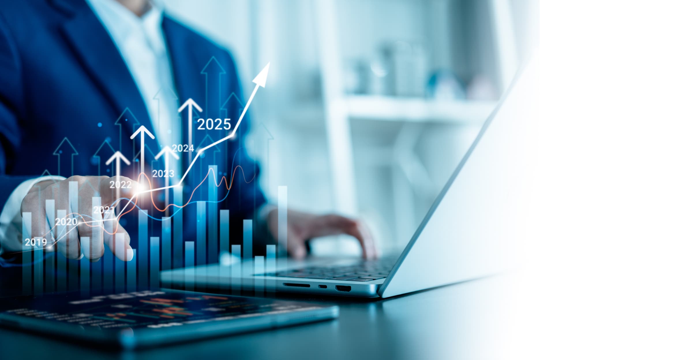 A person sat at a laptop with graphics of increasing bar charts in front of the screen