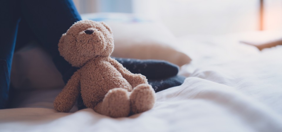 A small teddy bear lies against a child's foot