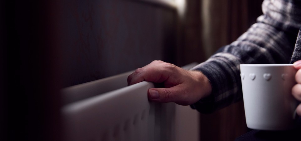 A hand on a radiator - the room looks cold