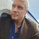 Professor Brian Haddock leans out of the window of a train carriage.