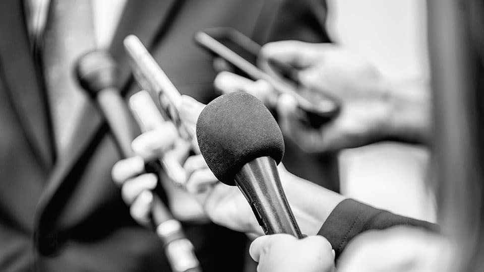 close up of a group of people holding recording equipment for an interview