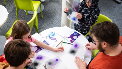 A group of young people and adults, exploring one of the exhibition activities