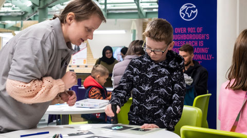 One of the researchers, guiding a young visitor through one of the exhibition activities