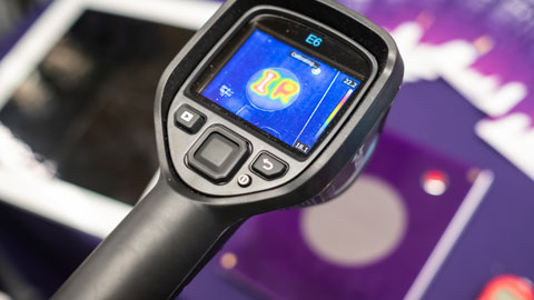 An infrared readout of items laid on a desk, including a brochure and electronic device. The latter produces a lighter (warmer) reading than the other objects.