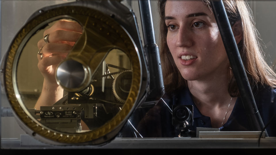 Close up shot of a student working in the NCCAT facilities, inspecting an circular engine part