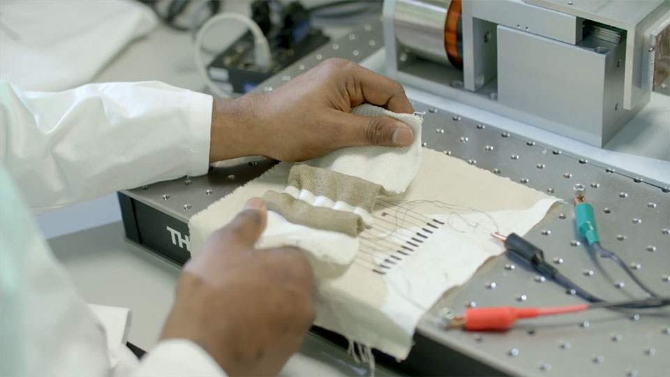 Two hands stretching a bionic bandage with electrical clips and wires attached
