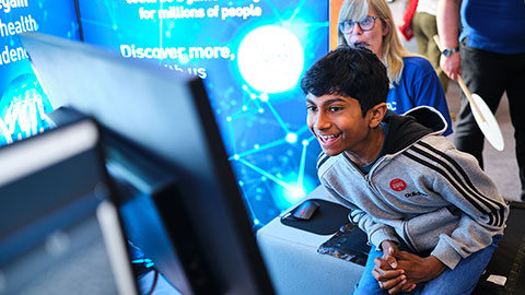 A boy laughing while sitting on an interactive seat, looking at a digital screen