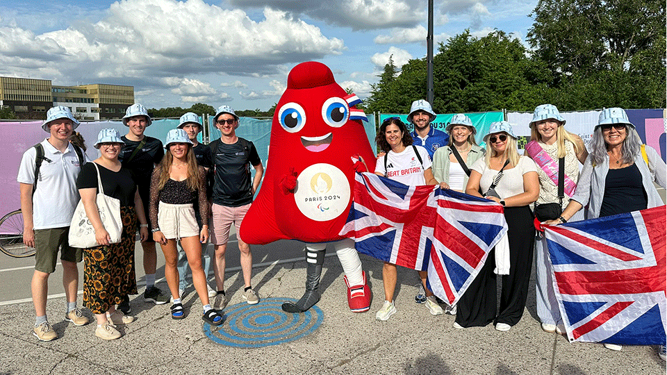 12 researchers with Paralympic mascot at Paris 2024 Games.
