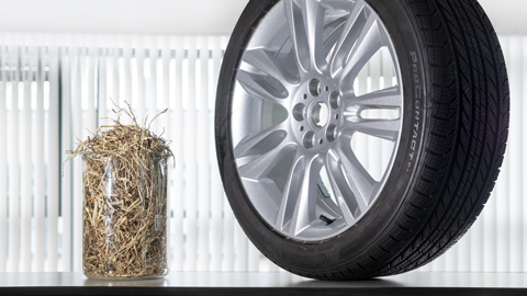A beaker of straw beside a car tyre