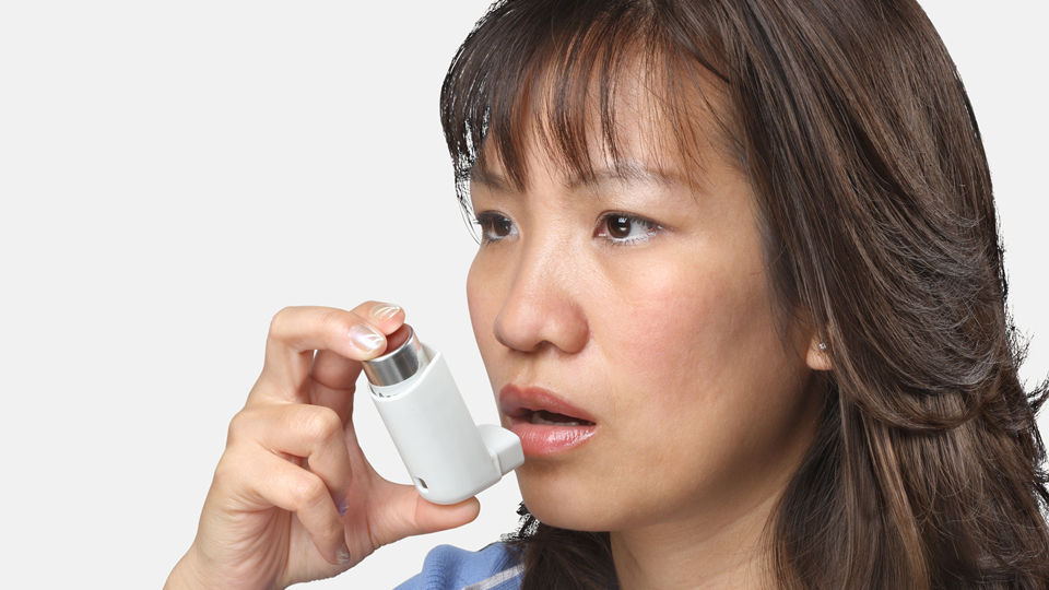 Photograph of a woman using an inhaler