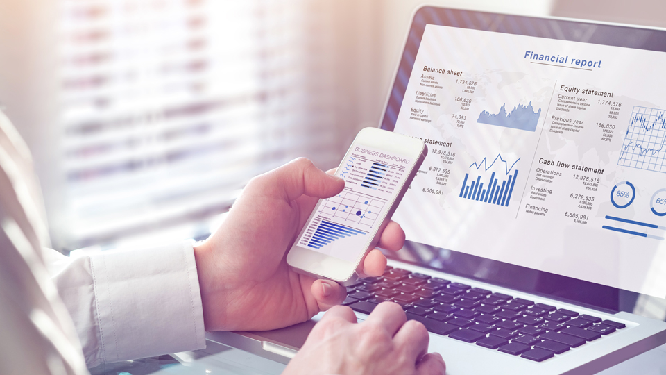 Close up of smart phone and laptop screens, showing financial reports