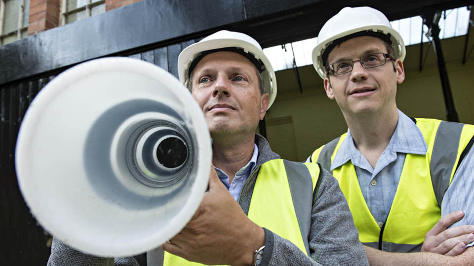 Researchers with a length of plastic water pipe