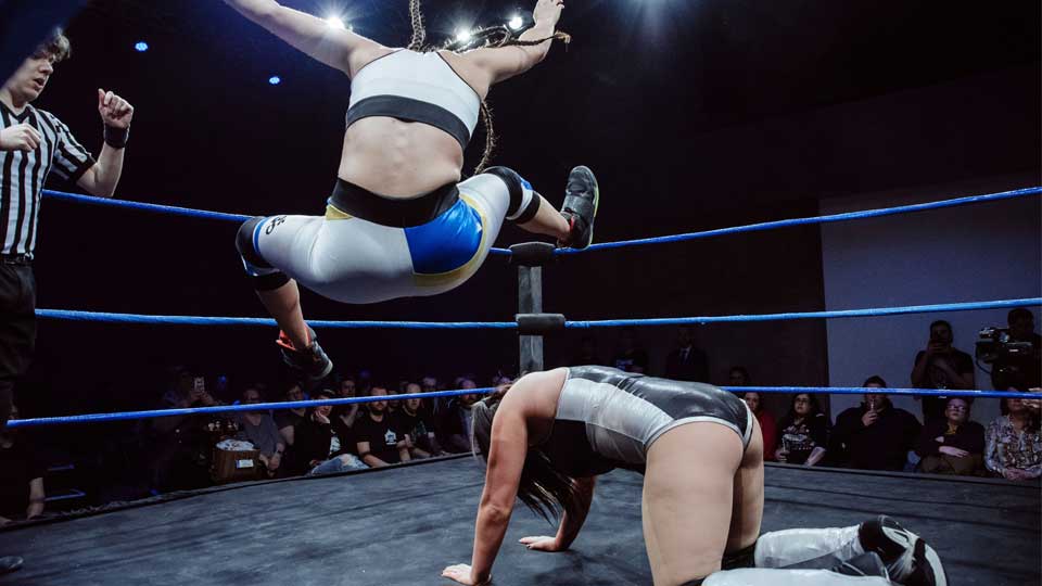 An exciting moment during a wrestling match as one wrestler leaps over another