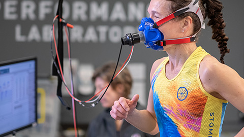 A female runner being monitored on a treadmill wearing a face mask being