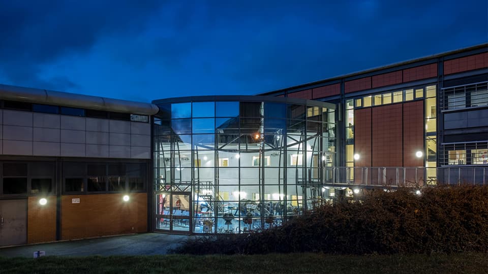 Stuart Miller building showing the penrose atrium from outside at dusk