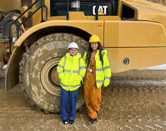Isabel and a colleague stood infront of a tractor
