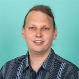 Headshot of Thomas with blue background