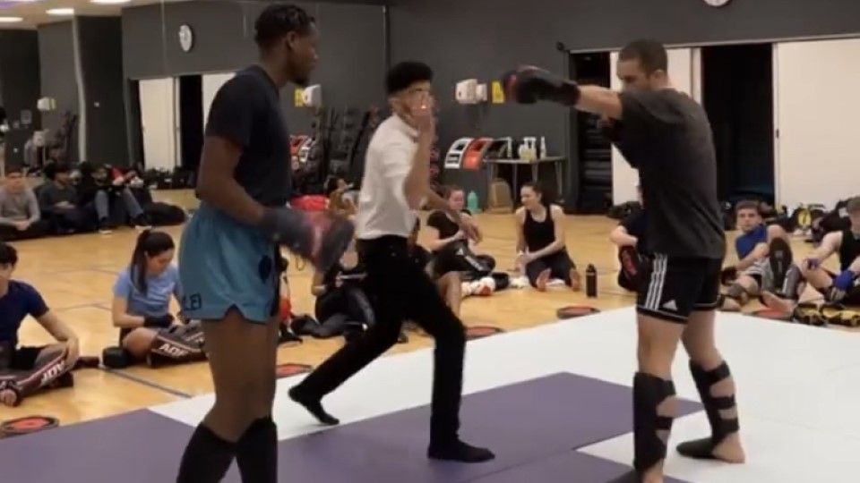 David is facing his opponent getting ready to kickbox by a referee